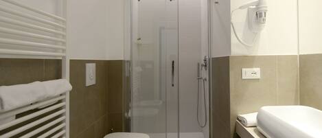 A modern bathroom with a glass-enclosed shower, a toilet, and a sink with a towel on the counter.