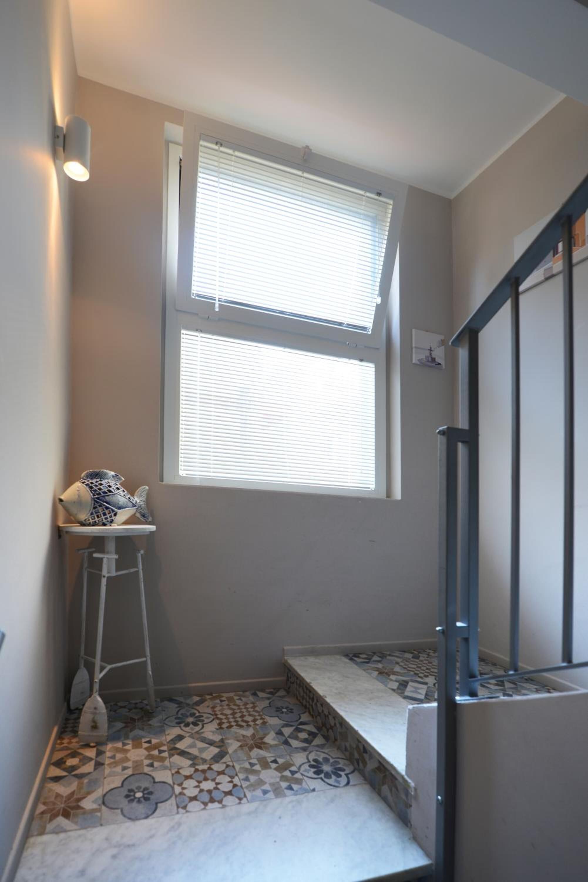 A small room with a window, a ladder, and a tiled floor.