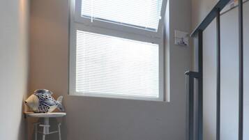 A small room with a window, a ladder, and a tiled floor.
