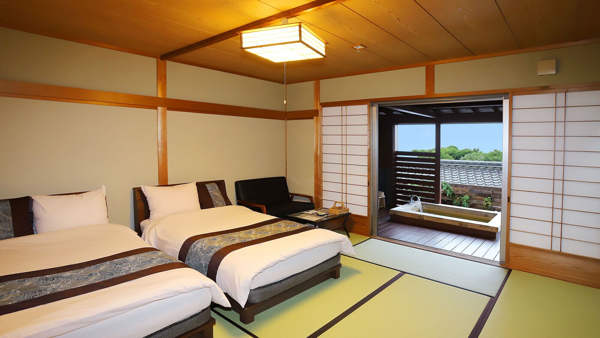 Una habitación tradicional japonesa con dos camas, una silla y un puertas correderas que dan a un balcón.