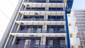 Een meerlaags gebouw met een modern architectonisch ontwerp, voorzien van meerdere balkons en grote ramen.