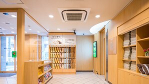 Een hotellobby met een receptiebalie, een muur met netjes opgevouwen handdoeken en een bord dat comfortabel slapen promoot.