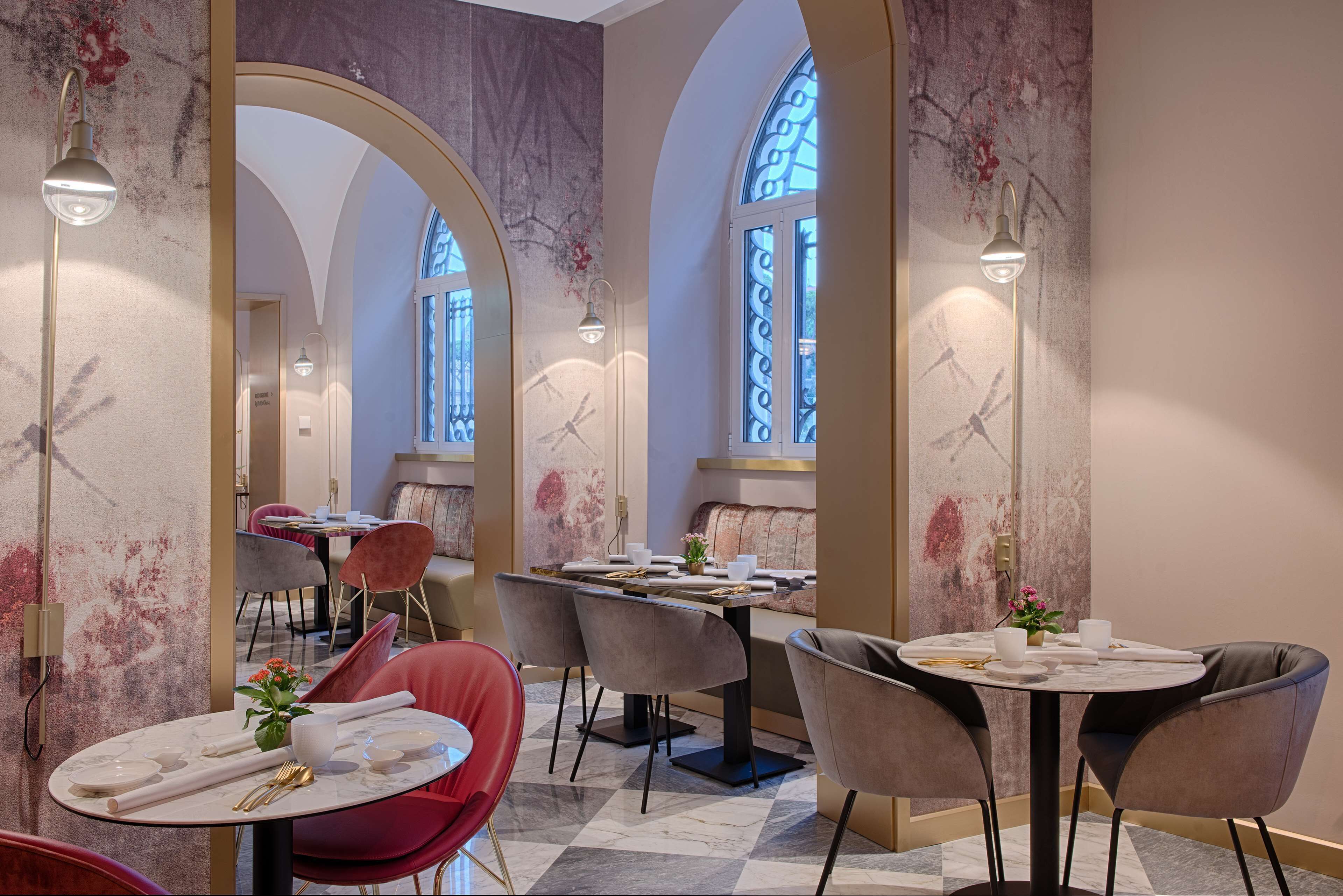 Un espace repas avec des tables rondes, des chaises et un lustre.