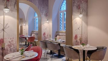 Un espace repas avec des tables rondes, des chaises et un lustre.