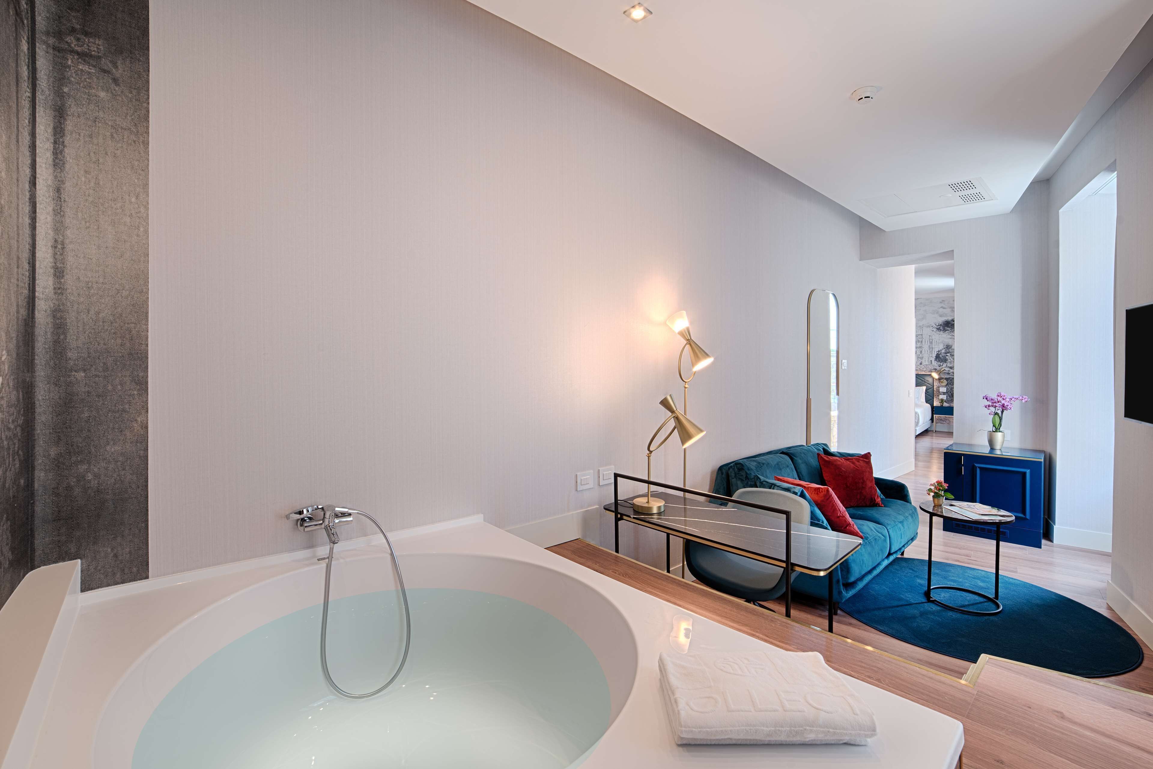 Une salle de bain moderne avec une grande baignoire, un canapé et une petite table.