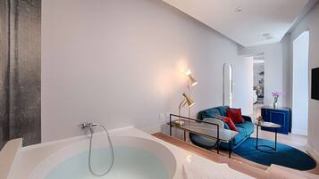 Une salle de bain moderne avec une grande baignoire, un canapé et une petite table.