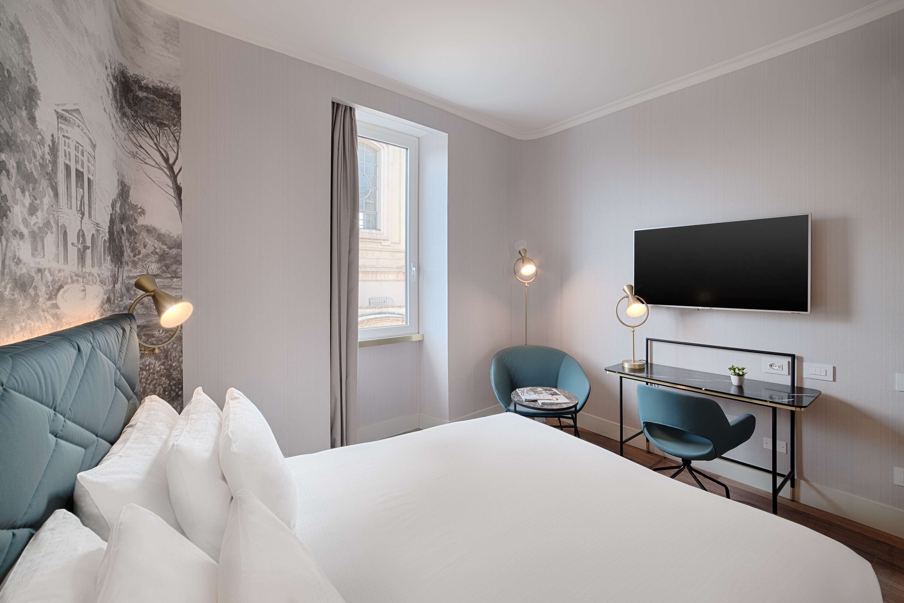 Une chambre d’hôtel avec un lit, un bureau et une chaise, une télévision et un tableau au mur.