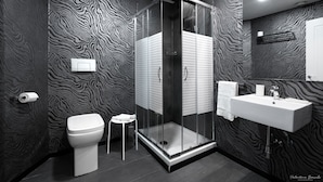 A modern bathroom with a zebra-patterned wall, a glass-enclosed shower, a white toilet, and a sink with a towel hanging on the wall. - Hotel Deco (Florence)