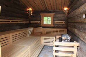 Een blokhut sauna met houten banken en een stenen vloer.
