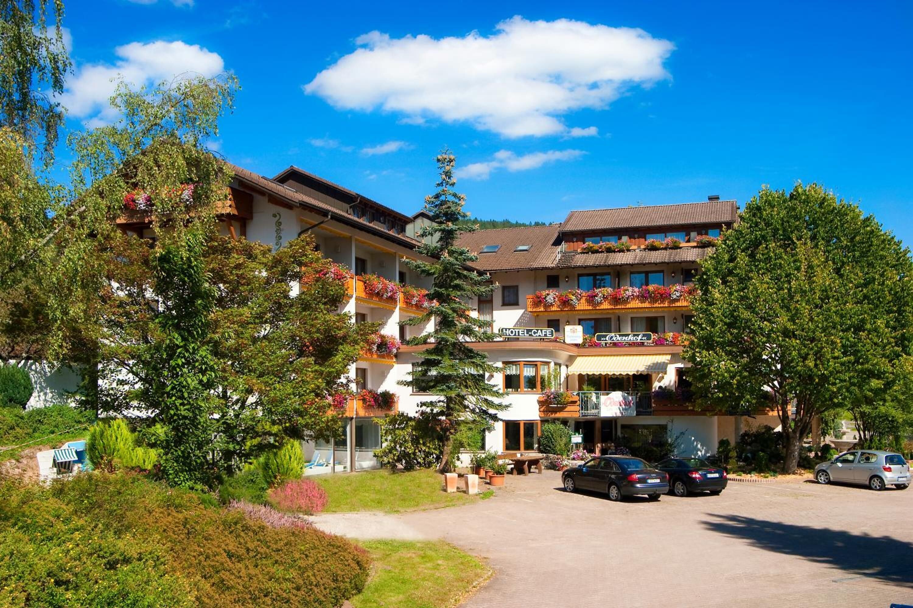 Ein Hotel mit mehreren Balkonen, einem Innenhof und einem Parkplatz.