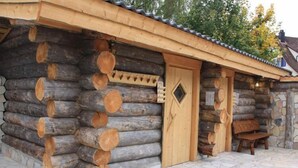 Una cabana de fusta amb fonaments de pedra, una porta de fusta i una boscada a l'exterior.