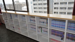 Une bibliothèque avec des étagères blanches remplies de livres et de magazines.