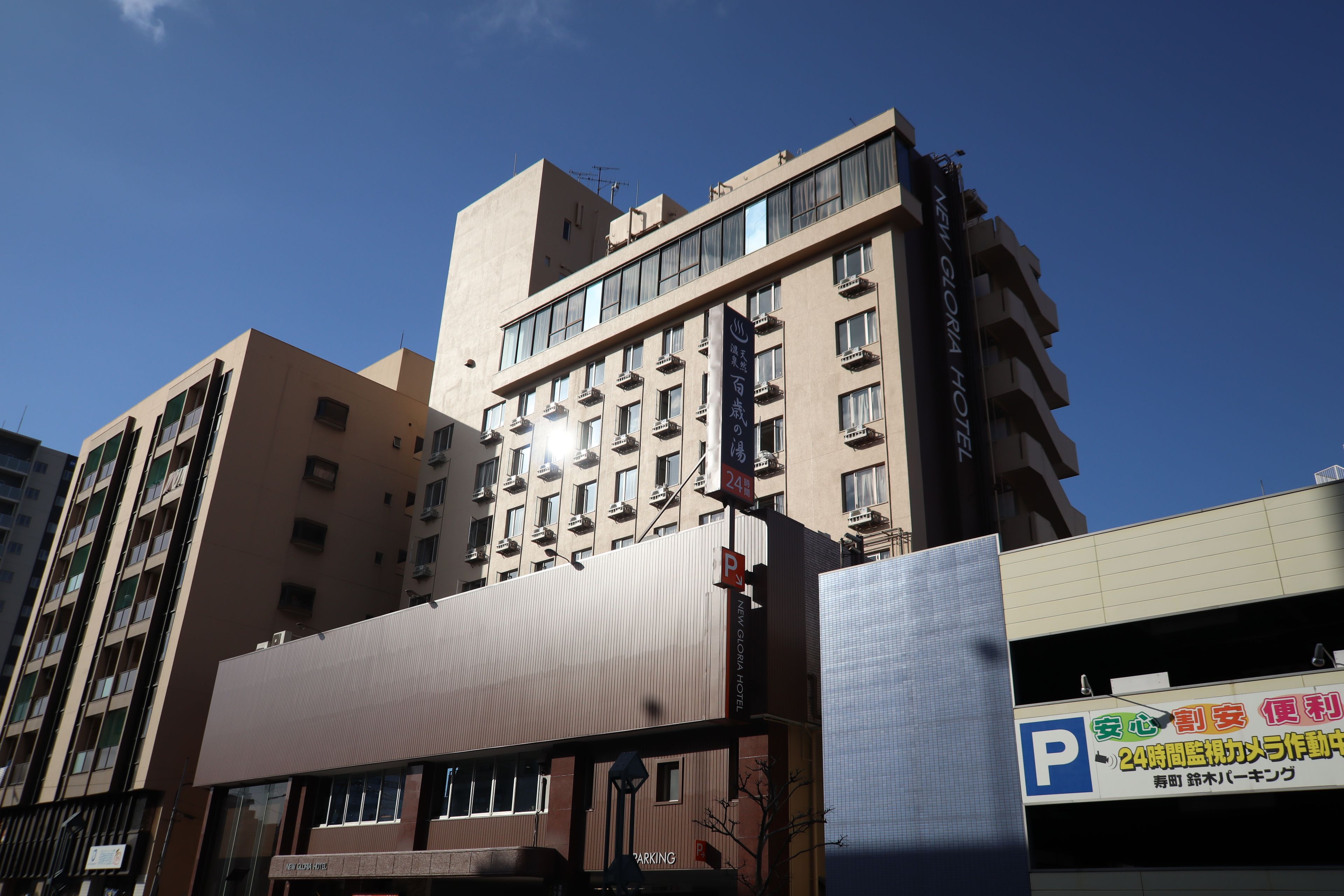 A multi-story hotel building with a prominent sign indicating it is the New Gloria Hotel.