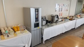 A buffet setup with a refrigerator, coffee maker, and various food items on a table. - New Gloria Oita Hotel (Oita)