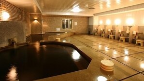 Un espace de bien-être comprenant un grand jacuzzi, des bancs en bois et un sol carrelé.