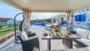 Un espace extérieur abrité comprenant une piscine, des chaises longues et une table à manger dressée pour le petit-déjeuner.