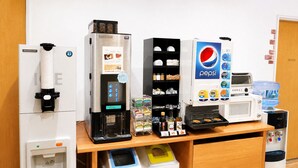 A coffee machine, a beverage dispenser, a microwave, and a water dispenser on a wooden counter. - REX INN Namba (Osaka)