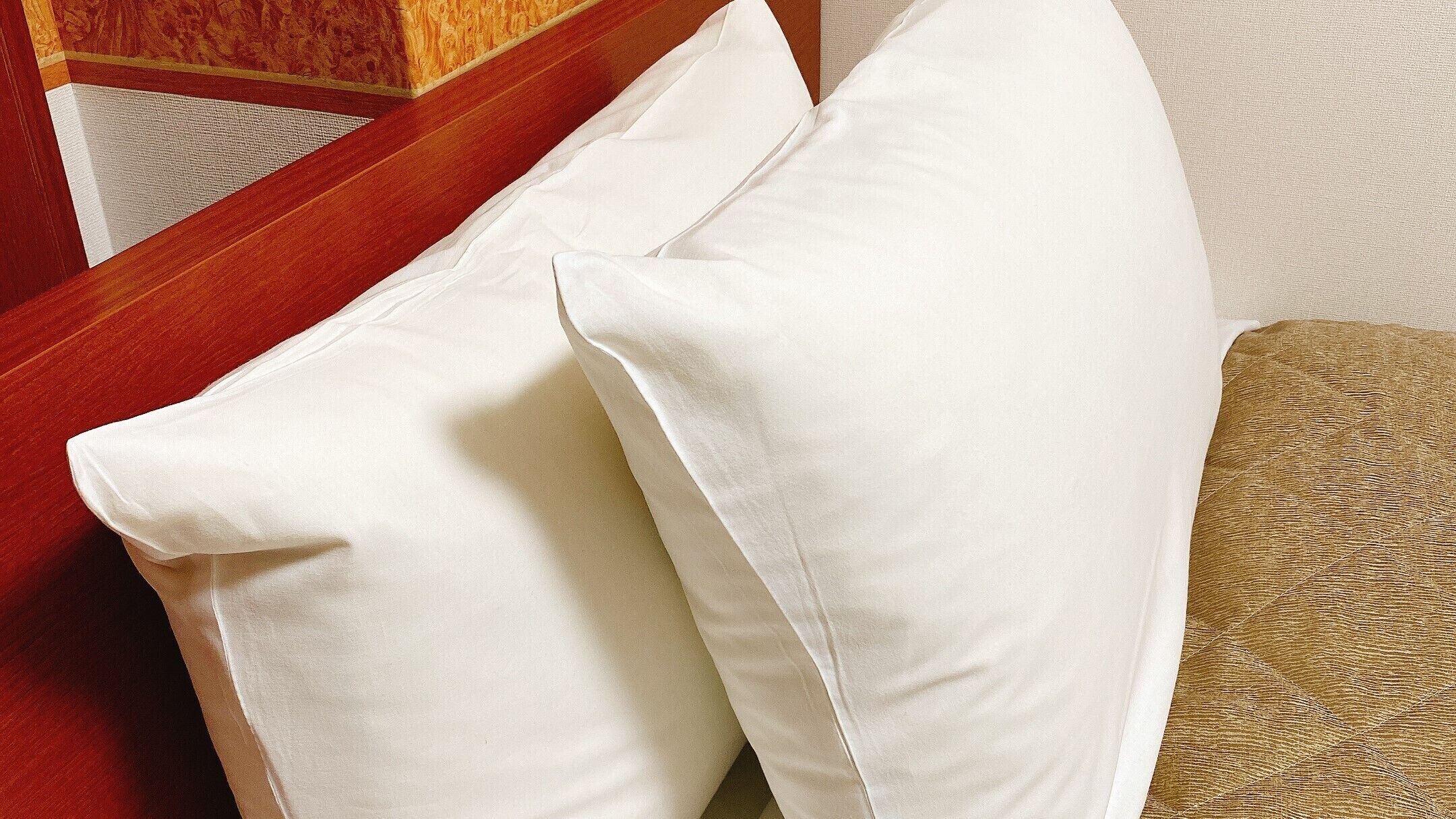 A close-up of a white pillow on a beige couch with a textured fabric.