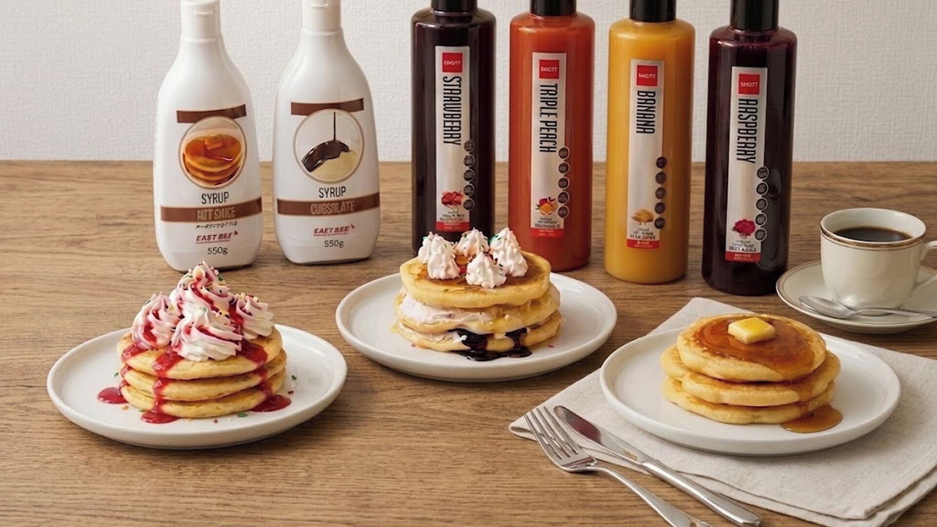 Une table avec des crêpes, des sirops et une tasse de café.