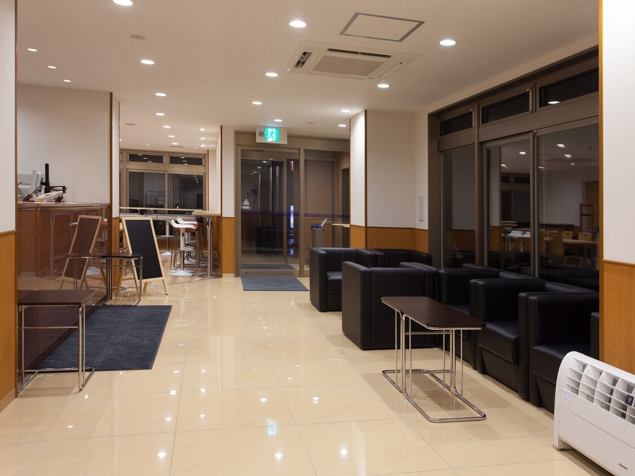 A hotel lobby with a reception desk, seating area, and a clear view into the dining area.