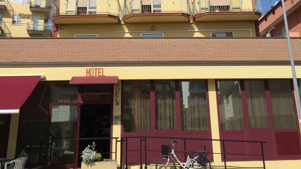 A hotel named Hotel Doel with a yellow facade, multiple balconies, and a bicycle parked outside. - Hotel Nuova Doel (Chioggia)