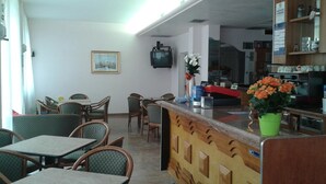 A hotel lobby with a reception desk, seating area with chairs and tables, a television mounted on the wall, and a framed picture on the wall. - Hotel Nuova Doel (Chioggia)