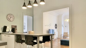 Et moderne køkken med bar, rustfrie hårde hvidevarer og hængende lamper.