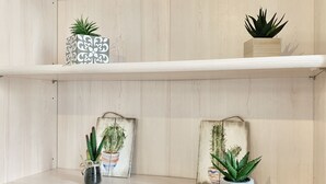 En træhylde med tre krukker med planter og en dekorativ æske.