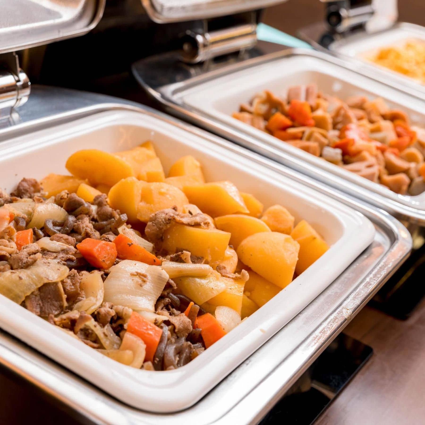 A buffet with various dishes including meat, potatoes, and vegetables.