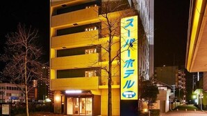 Un edificio de varios pisos con un letrero amarillo llamativo en la parte superior y un gran letrero iluminado en el lateral.