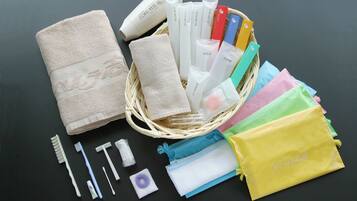 A variety of personal care items including a towel, toothbrushes, and grooming products arranged on a dark surface.