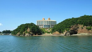 A large hotel with multiple floors, situated on a hillside overlooking a body of water. - Resort Club Iseshima (Shima)