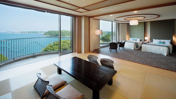 A hotel room with a large balcony, a bed, a desk, and a view of the sea. - Resort Club Iseshima (Shima)
