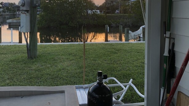 A patio with a water feature, a fire extinguisher, and a view of a sunset over a body of water.
