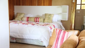 A bedroom with a bed, pillows, a bedside table, and a window.
