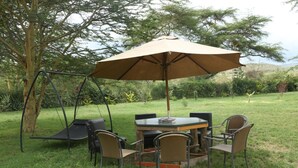 An outdoor seating area with a swing set, a round table, and four chairs.