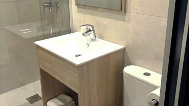 A modern bathroom with a wooden vanity, a glass shower enclosure, and a toilet. - Hôtel Les Rives Bleues (La Grande-Motte)
