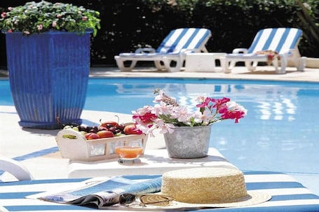 Una piscina al aire libre, sillones reclinables de piscina