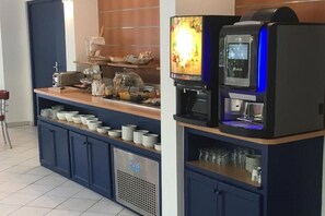 A self-service beverage station with a coffee machine, a TV screen, and a variety of cups and glasses. - Hôtel Les Rives Bleues (La Grande-Motte)