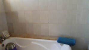 A bathroom with a bathtub, a blue towel, and a purple object on the edge. - Orange Groove Hotel (Kaduna)