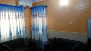 A room with two sofas, a ceiling fan, and a wall-mounted air conditioner. - Orange Groove Hotel (Kaduna)