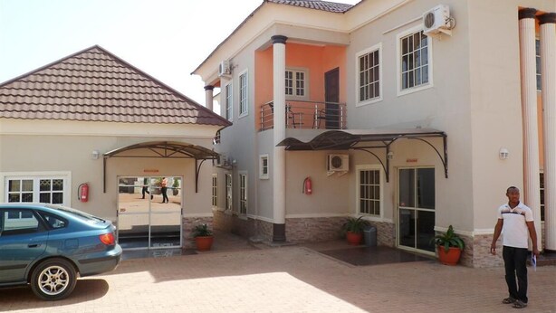 A building with a tiled roof, a covered entrance, and potted plants. - Orange Groove Hotel (Kaduna)