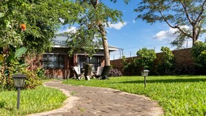 A pathway leading to a house with a brick wall and a metal roof.