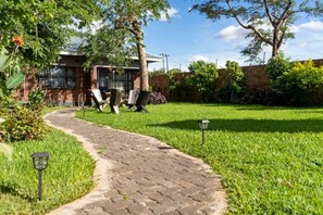 A brick pathway leading to a house with a garden, a lawn, and a brick wall. - KhayaLethu -Beautiful Family Holiday Home (Victoria Falls)