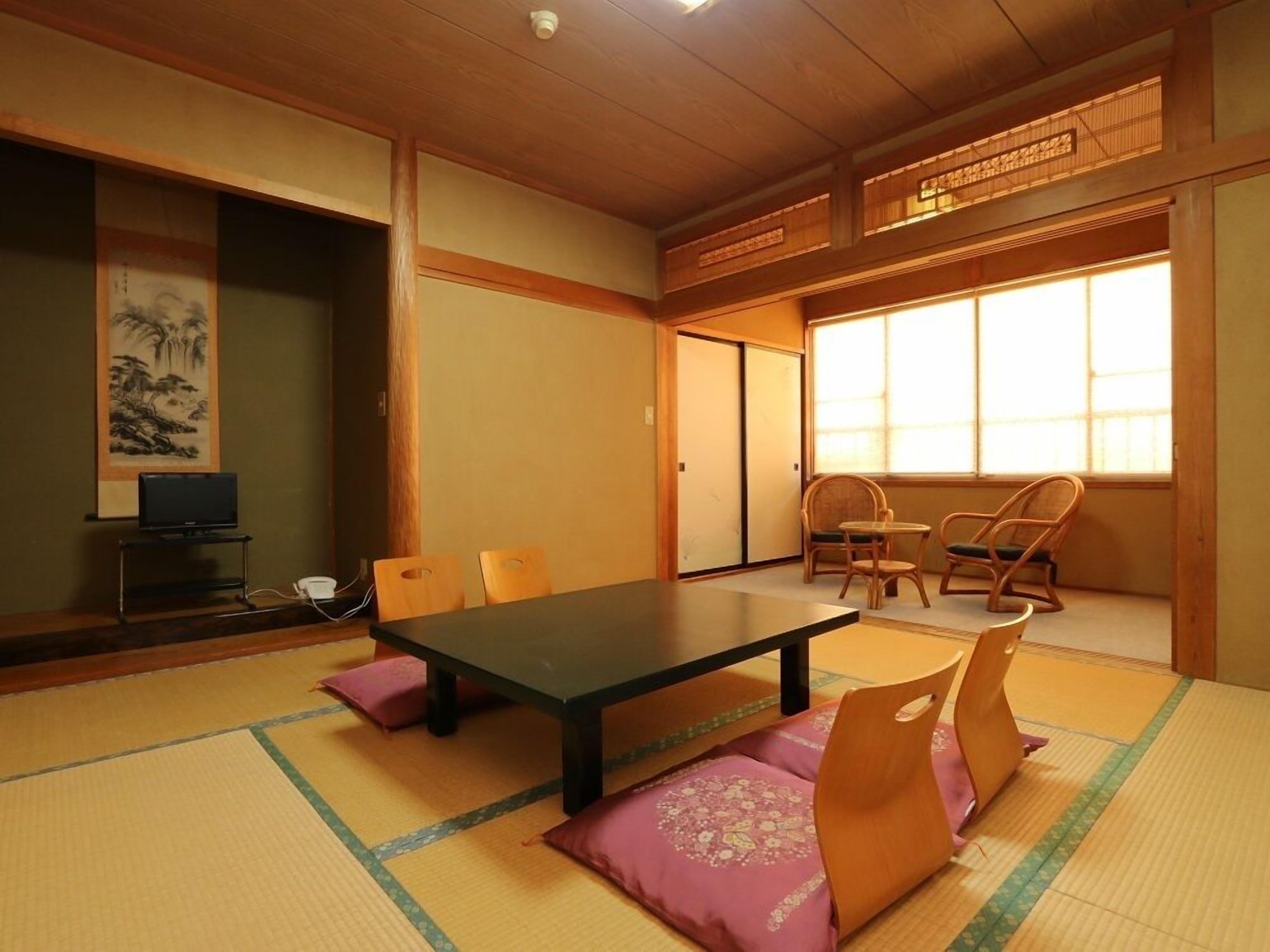 Una habitación japonesa tradicional con suelo de tatami, una mesa baja y dos sillas.