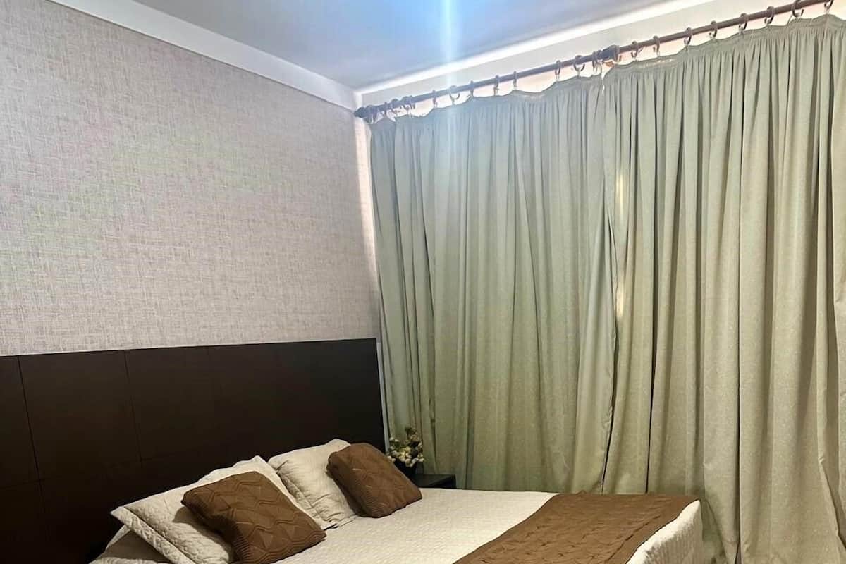 Ein Hotelzimmer mit einem Bett, einem kleinen Tisch und Vorhängen.