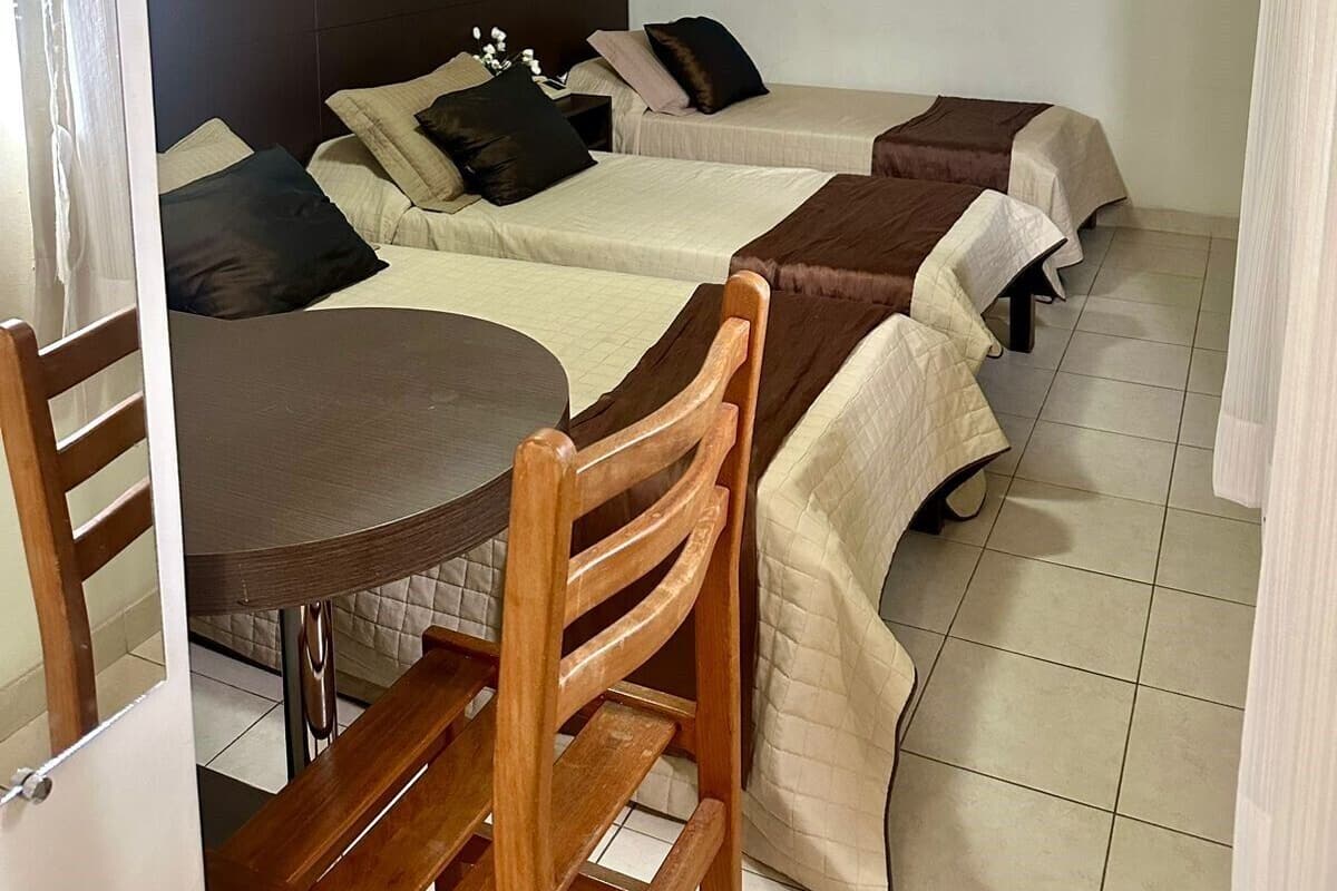 Ein Zimmer mit zwei Betten, einem Tisch und einem Deckenventilator.
