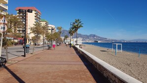 A coastal promenade with a stone wall, palm trees, and a clear view of the sea. - Quiet Beachfront Oasis : Doña Sofía (Fuengirola)