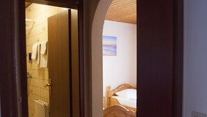 A hallway leading to a bedroom with a wooden bed and a radiator. - Gästehaus Häuser (Linden)