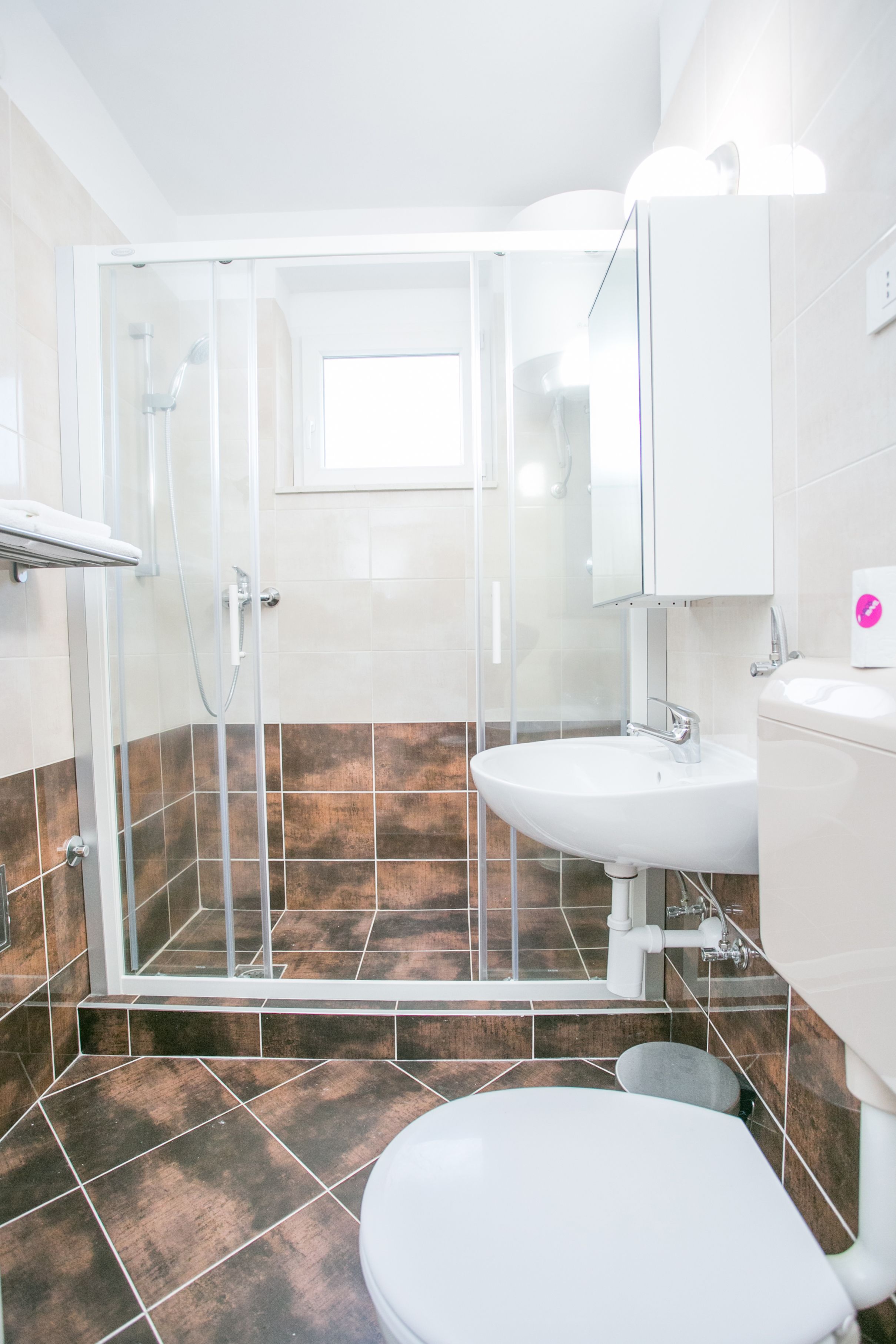 A bathroom with a shower, toilet, sink, and a mirror.